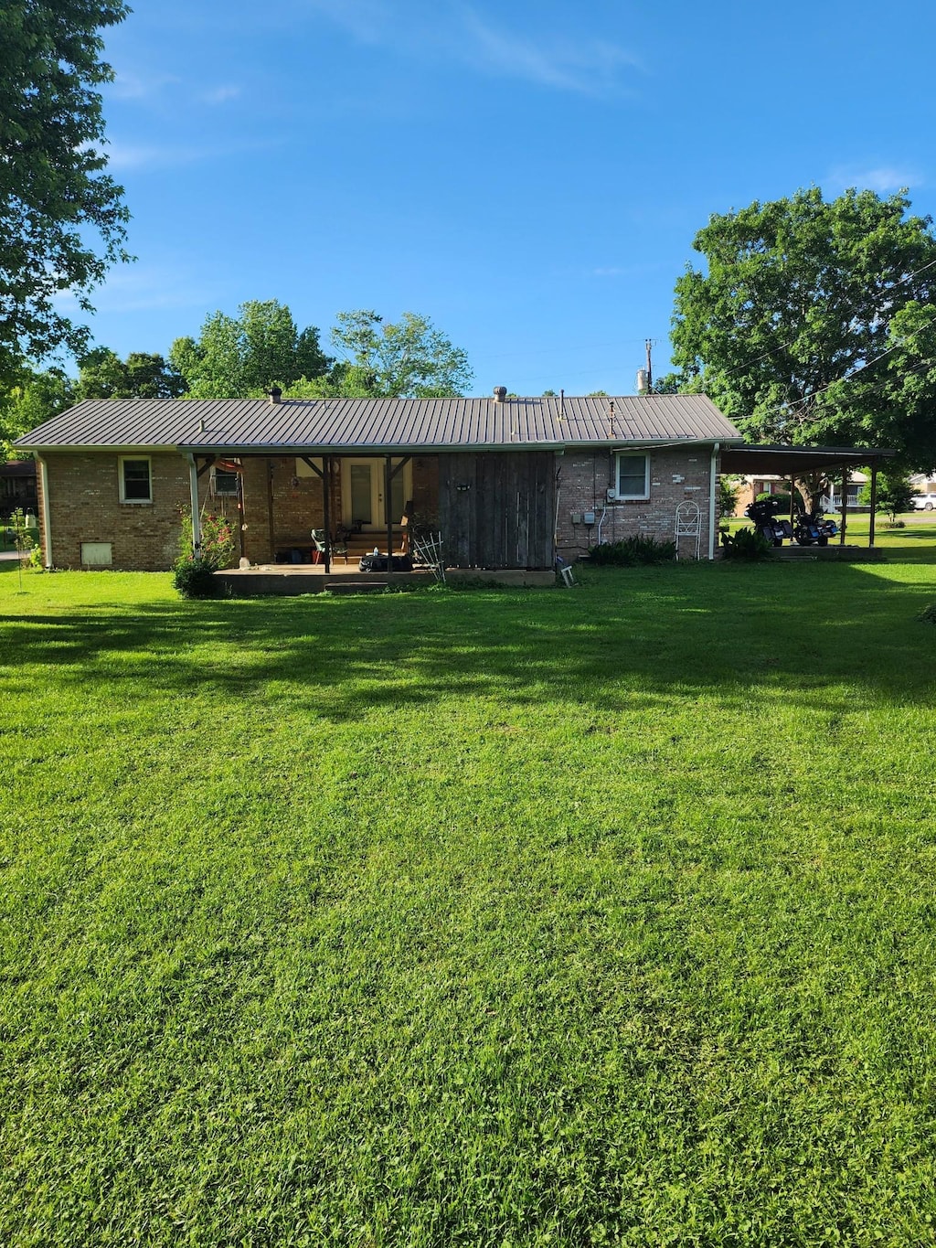 348 Leader Dr, New Johnsonville, TN 37134 - rear view of property featuring a lawn, metal roof, brick siding, a standing seam roof, and a chimney