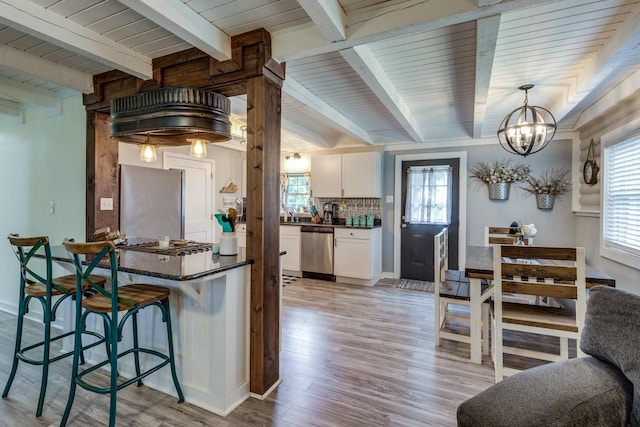 7547 Elm Springs Rd, Orlinda, TN 37141 - kitchen featuring appliances with stainless steel finishes, dark countertops, a chandelier, a breakfast bar, and a wood ceiling with exposed beams