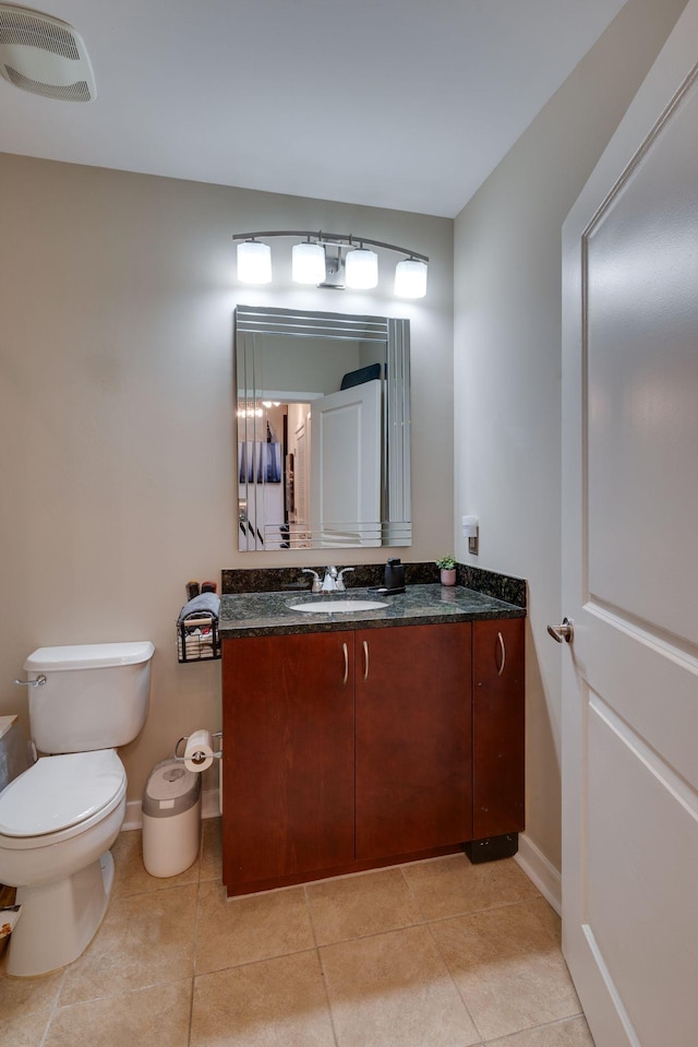 half bathroom featuring toilet, vanity, baseboards, and tile patterned flooring