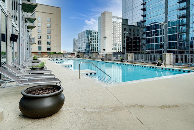 community pool featuring a city view, fence, and a patio area