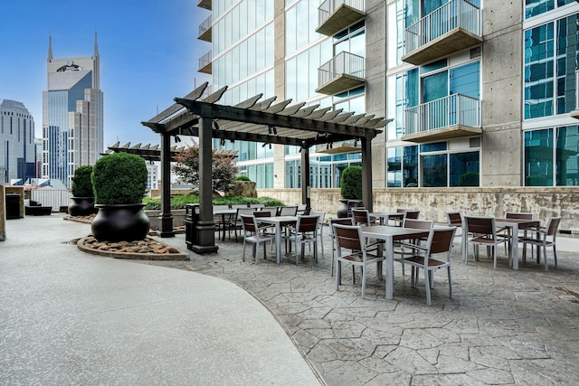 view of patio / terrace with a pergola, outdoor dining area, and a view of city