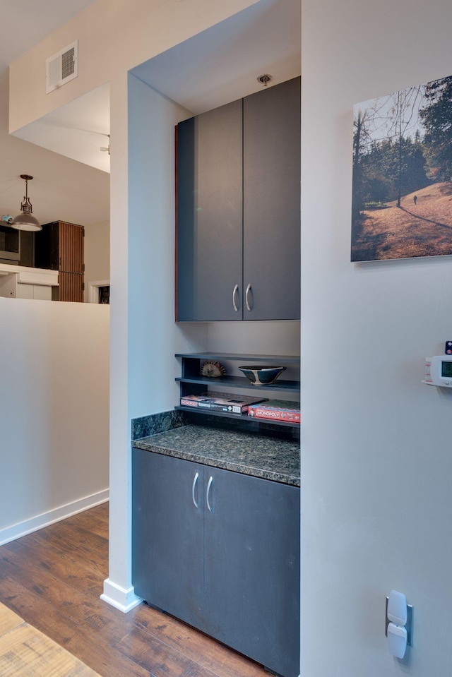 kitchen featuring wood finished floors, dark countertops, and baseboards