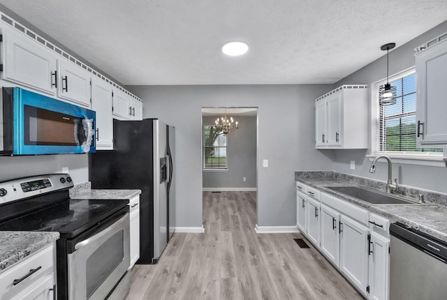 6109 Ebenezer Rd, Greenbrier, TN 37073 - kitchen featuring stainless steel appliances, a sink, a chandelier, light wood finished floors, and white cabinetry