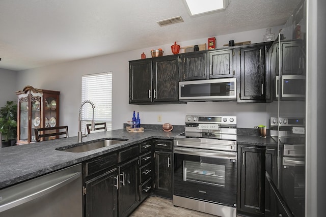 5943 Colchester Dr, Hermitage, TN 37076 - kitchen with stainless steel appliances, a sink, dark cabinetry, and light wood-style floors
