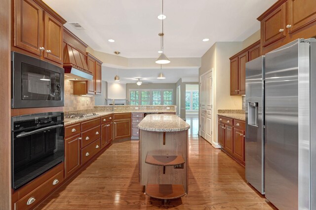 221 Antebellum Ln, Mount Juliet, TN 37122 - kitchen with black appliances, a peninsula, light wood-style floors, premium range hood, and backsplash