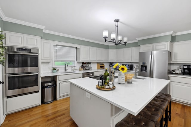 503 Dawn Pl, Lebanon, TN 37087 - kitchen featuring appliances with stainless steel finishes, a sink, a chandelier, ornamental molding, and a kitchen breakfast bar