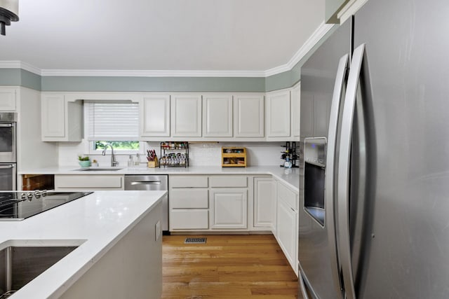 503 Dawn Pl, Lebanon, TN 37087 - kitchen with appliances with stainless steel finishes, crown molding, a sink, light wood finished floors, and white cabinetry