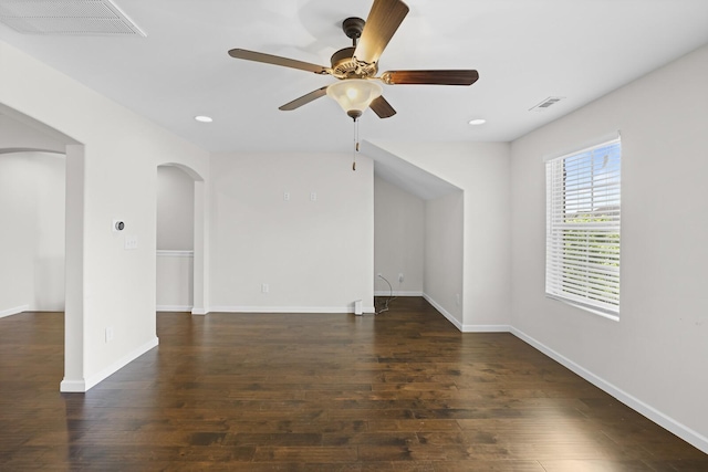 empty room featuring arched walkways, a ceiling fan, wood finished floors, recessed lighting, and baseboards