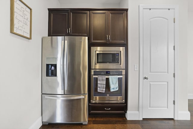 kitchen featuring appliances with stainless steel finishes, dark brown cabinetry, baseboards, and dark wood-type flooring