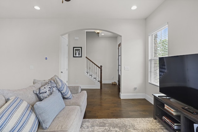 living area with arched walkways, stairs, wood finished floors, recessed lighting, and baseboards