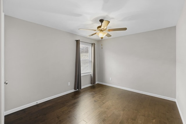 empty room featuring a ceiling fan, dark wood-style flooring, and baseboards