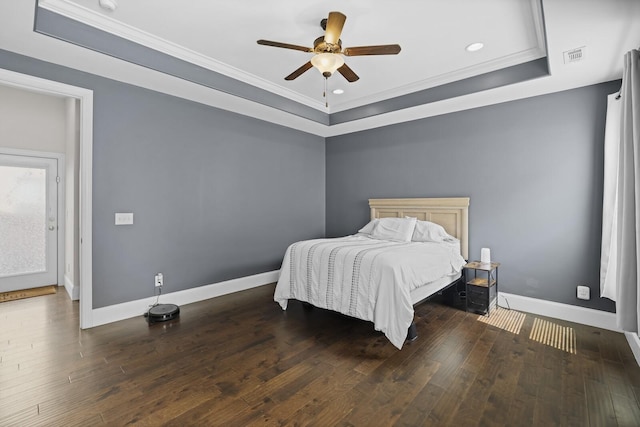 bedroom featuring a raised ceiling, crown molding, wood finished floors, baseboards, and recessed lighting