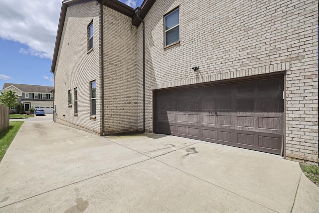 view of home's exterior with brick siding, a garage, and concrete driveway