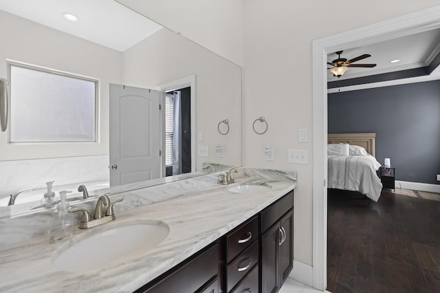 ensuite bathroom with ceiling fan, double vanity, and baseboards