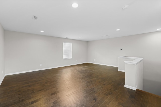 empty room with dark wood-type flooring, baseboards, and recessed lighting