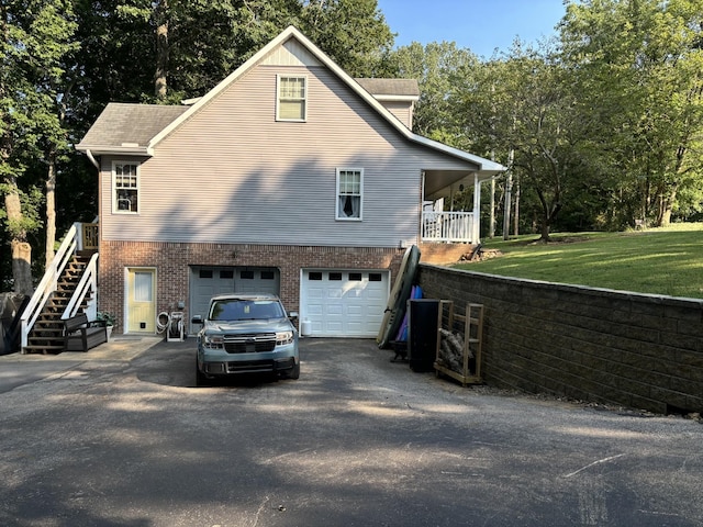 434 Hickman Shores Rd, Dover, TN 37058 - view of side of home featuring driveway, an attached garage, stairway, brick siding, and view of wooded area