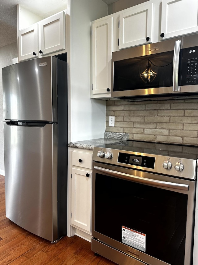 1321 Rickman Rd, Livingston, TN 38570 - kitchen featuring stainless steel appliances, white cabinetry, dark wood finished floors, decorative backsplash, and light stone countertops