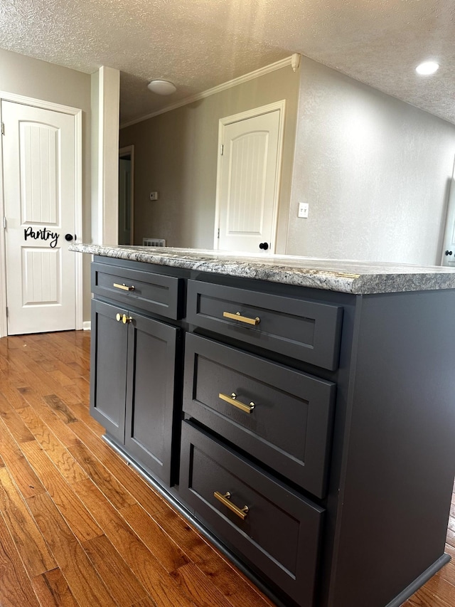 1321 Rickman Rd, Livingston, TN 38570 - kitchen with a textured ceiling, wood finished floors, gray cabinets, ornamental molding, and light stone countertops