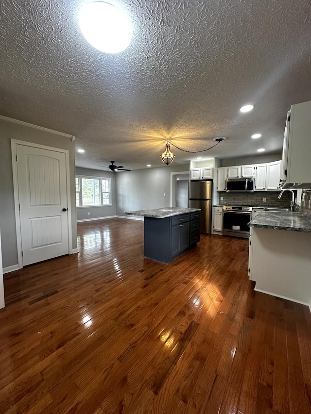 1321 Rickman Rd, Livingston, TN 38570 - kitchen with stainless steel appliances, a textured ceiling, open floor plan, a center island, and dark wood-style floors