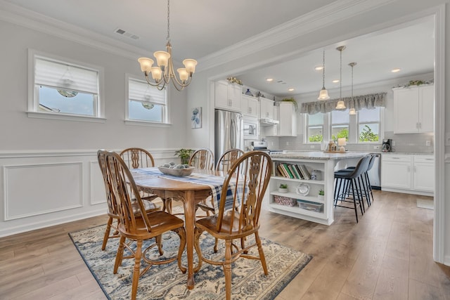 1514 Bledsoe Knl, Spring Hill, TN 37174 - dining room featuring a chandelier, crown molding, light wood-style flooring, a wainscoted wall, and a decorative wall