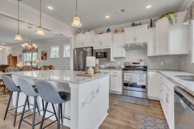 1514 Bledsoe Knl, Spring Hill, TN 37174 - kitchen with stainless steel appliances, under cabinet range hood, ornamental molding, a center island, and backsplash