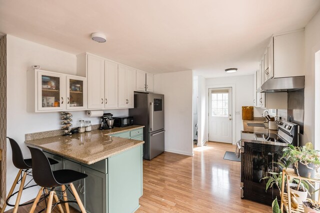 1114 Kingston Springs Rd, Kingston Springs, TN 37082 - kitchen with under cabinet range hood, appliances with stainless steel finishes, white cabinets, a peninsula, and a kitchen bar