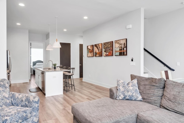 living area with light wood-style flooring, recessed lighting, baseboards, and stairway
