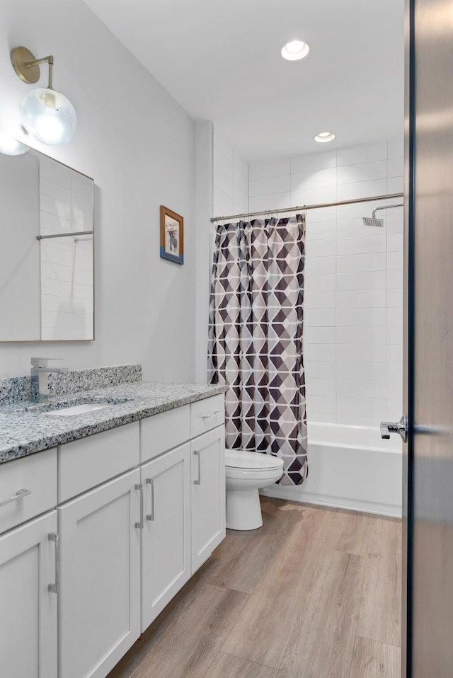 bathroom with wood finished floors, toilet, recessed lighting, vanity, and shower / tub combo