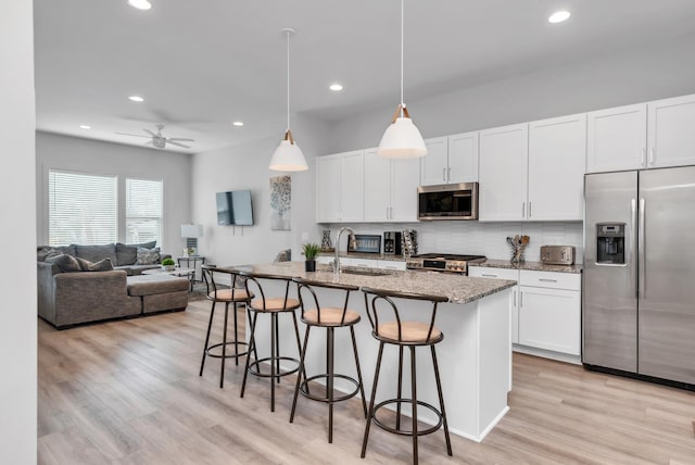 kitchen featuring appliances with stainless steel finishes, a sink, a breakfast bar area, recessed lighting, and decorative backsplash