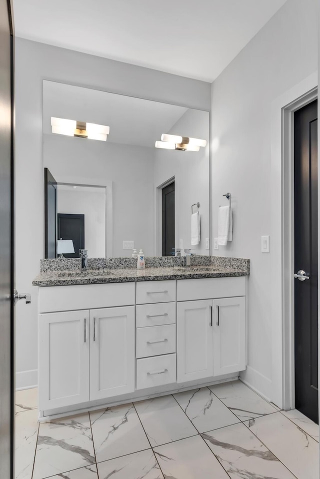 bathroom with marble finish floors, double vanity, and baseboards