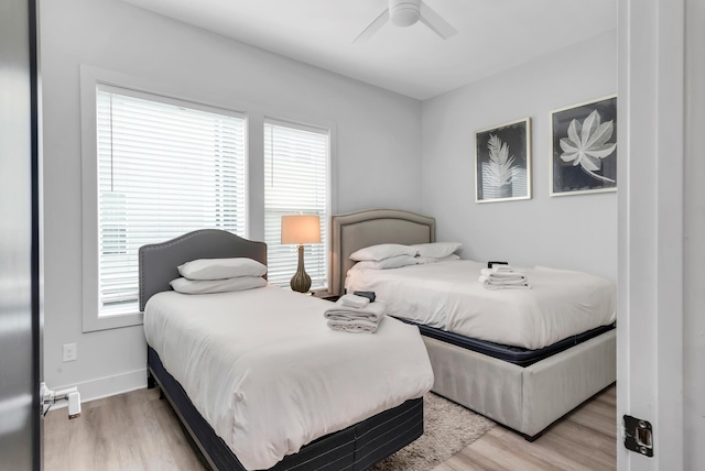 bedroom featuring wood finished floors, multiple windows, and a ceiling fan