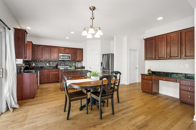 1201 Banbury Row, Brentwood, TN 37027 - kitchen featuring appliances with stainless steel finishes, dark countertops, a chandelier, light wood-style flooring, and backsplash