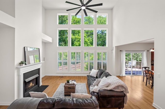 1201 Banbury Row, Brentwood, TN 37027 - living room with a towering ceiling, a ceiling fan, a fireplace with flush hearth, wood finished floors, and baseboards