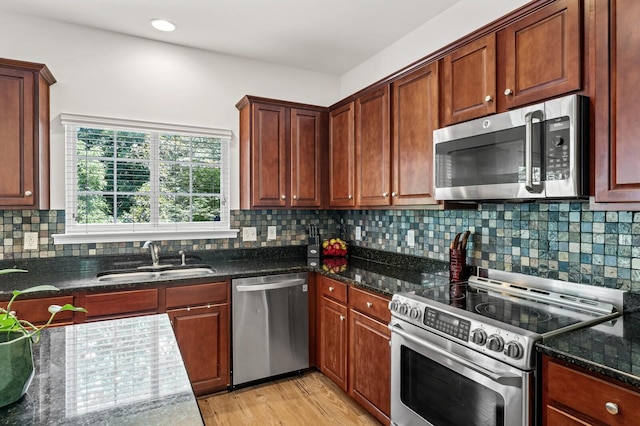 1201 Banbury Row, Brentwood, TN 37027 - kitchen featuring appliances with stainless steel finishes, a sink, light wood finished floors, dark stone countertops, and backsplash