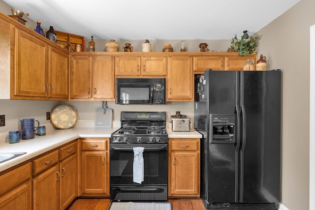 1325 Branchside Ct, Thompsons Station, TN 37179 - kitchen featuring black appliances, light countertops, wood finished floors, and brown cabinetry
