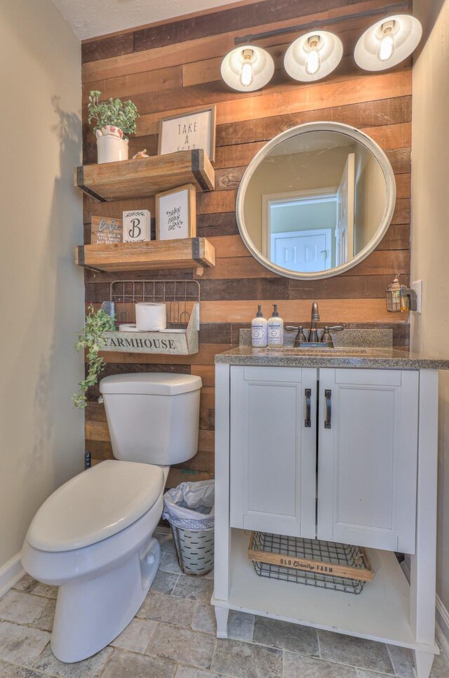 1753 Stone Hollow Ct, Hermitage, TN 37076 - bathroom featuring wooden walls, vanity, toilet, baseboards, and stone finish flooring