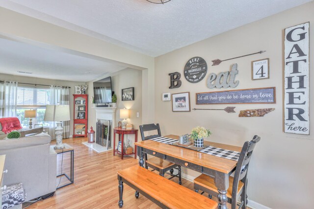 1753 Stone Hollow Ct, Hermitage, TN 37076 - dining space with light wood-style flooring, a fireplace, and a textured ceiling