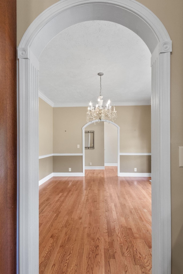 134 Blackberry Ln, Murfreesboro, TN 37130 - empty room featuring arched walkways, a chandelier, light wood finished floors, crown molding, and baseboards