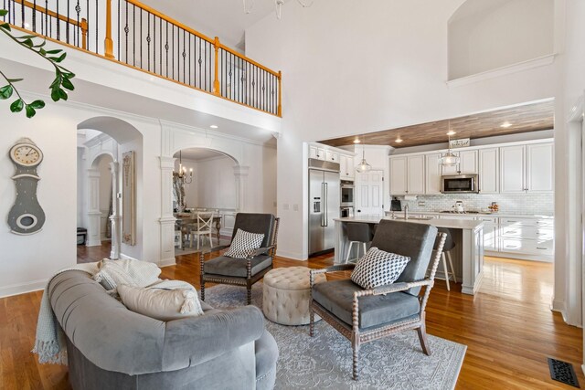 1505 Charleston Park Dr, Spring Hill, TN 37174 - living area with arched walkways, a towering ceiling, light wood-type flooring, a chandelier, and baseboards