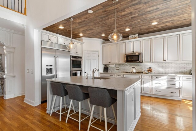 1505 Charleston Park Dr, Spring Hill, TN 37174 - kitchen featuring stainless steel appliances, a sink, decorative columns, a kitchen bar, and light wood-style flooring
