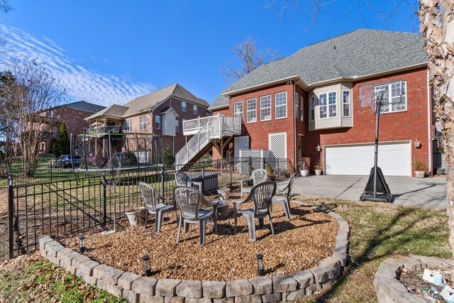 1505 Charleston Park Dr, Spring Hill, TN 37174 - back of house with an outdoor fire pit, brick siding, an attached garage, fence, and driveway