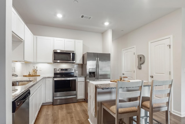 105 Grayson Cir, Chapel Hill, TN 37034 - kitchen featuring appliances with stainless steel finishes, a sink, a breakfast bar area, light wood finished floors, and light stone counters