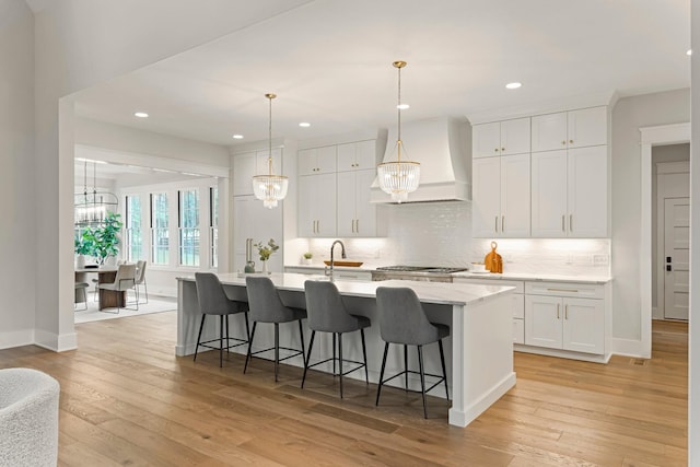 4617 Delta Springs Ln, Franklin, TN 37064 - kitchen featuring custom exhaust hood, a kitchen island with sink, a kitchen breakfast bar, white cabinetry, and recessed lighting