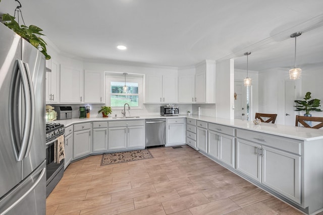 106 Lakewood Dr, Dickson, TN 37055 - kitchen with stainless steel appliances, a sink, a peninsula, light countertops, and pendant lighting