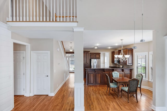 dining room featuring light wood finished floors, baseboards, a chandelier, and a towering ceiling