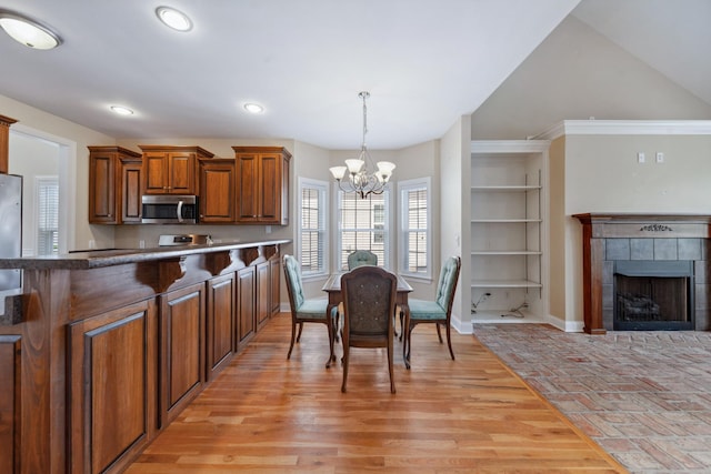 kitchen with stainless steel appliances, a chandelier, brown cabinets, hanging light fixtures, and baseboards