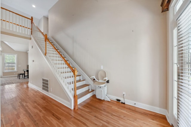 staircase with wood finished floors, baseboards, and recessed lighting
