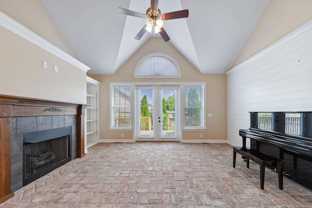 living area featuring brick flooring, a ceiling fan, a tiled fireplace, french doors, and baseboards