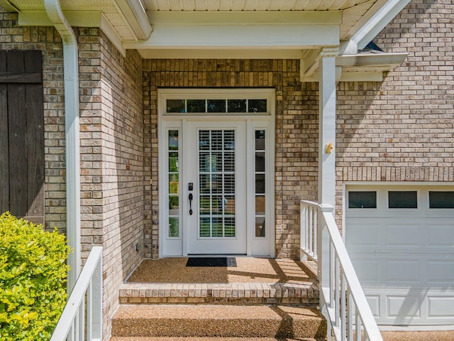 doorway to property featuring brick siding and a garage