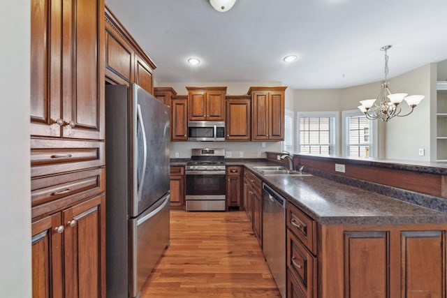 kitchen with stainless steel appliances, a sink, dark countertops, brown cabinetry, and recessed lighting
